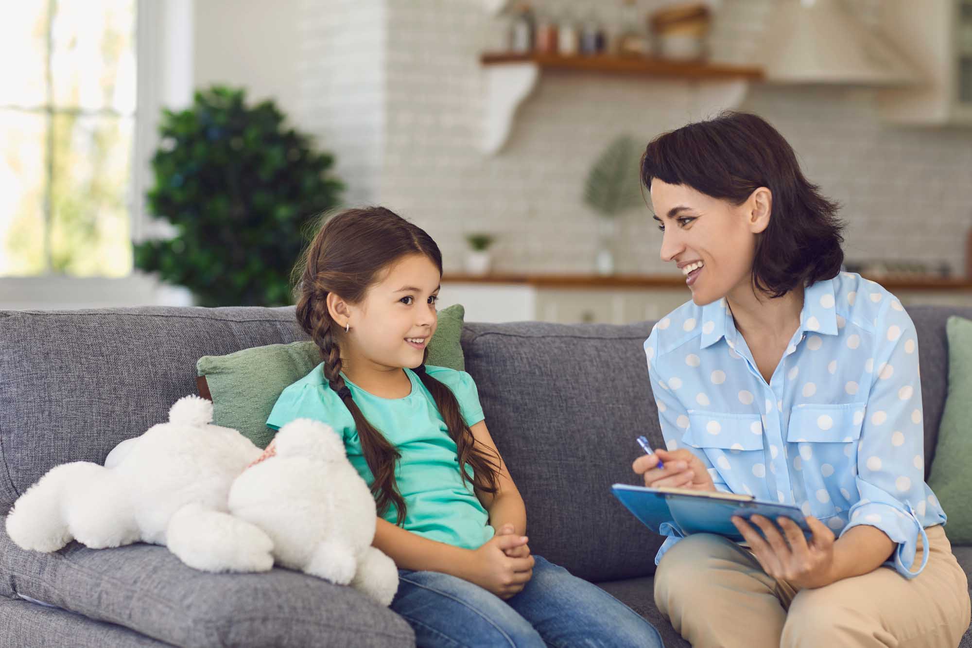 Smiling little girl talks to a cheerful child psychotherapist during a therapy session in the office. Mountains ABA ABA Therapy in New Hampshire25
